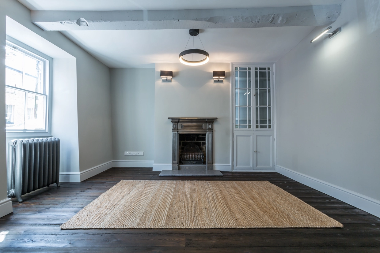 Renovated living space showing fireplace, modern lighting and radiator