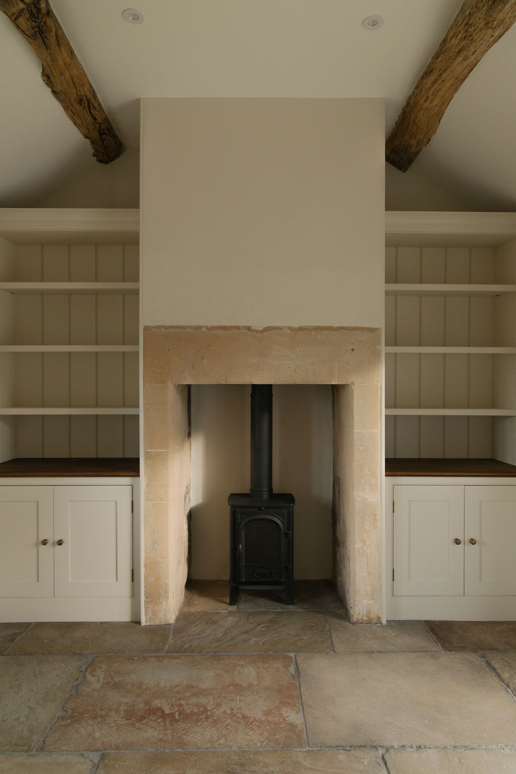 Living room with restored fireplace, alcove shelves and wood beams