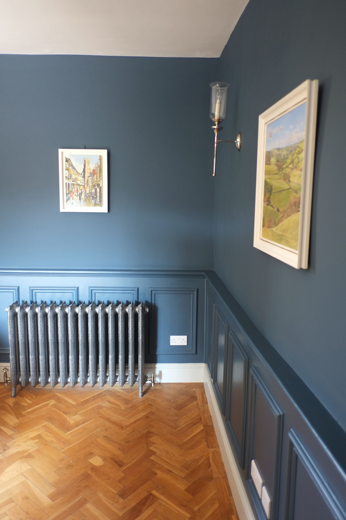 Interior living area view, showing wood panel, parquet floor, and traditional radiator